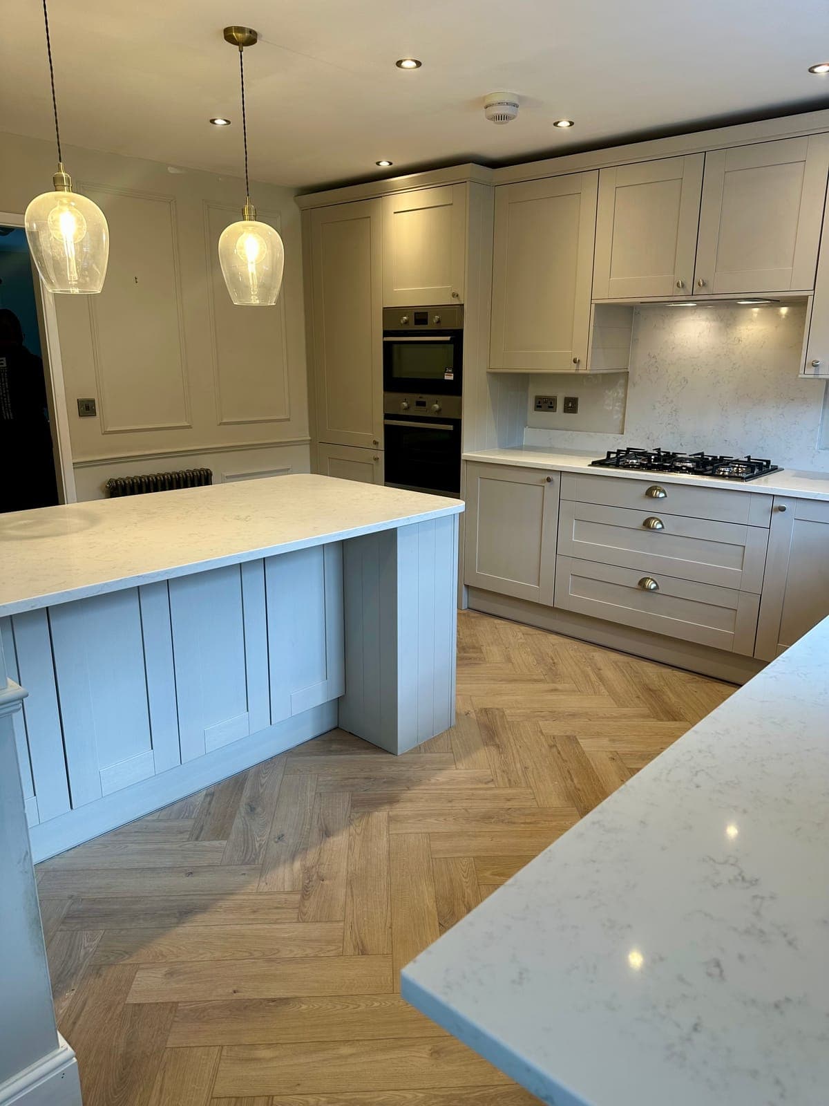 Bespoke sage shaker kitchen with island and herringbone flooring